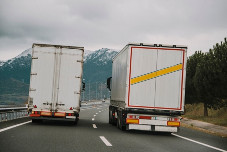 Two large trucks side by side on the highway