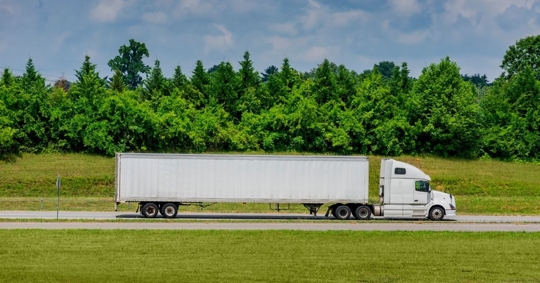 an 18-wheeler driving down a rural road