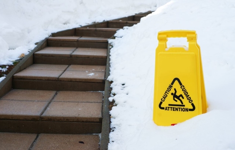 slip and fall sign on snow beside walkway